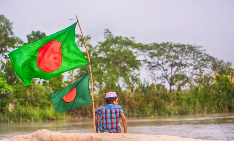 boy is sitting waving the flag of bangladesh